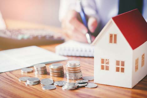 Model of a house and coins on a table